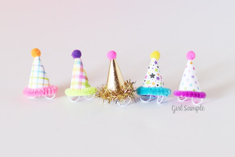May include: Five colorful party hats with different patterns and pom-poms on top. The hats are made of paper and have a fuzzy trim around the bottom.