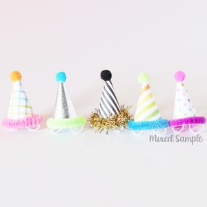 May include: Six colorful party hats with different patterns and pom-poms on top. The hats have a fuzzy trim around the bottom.  Mixed Sample.