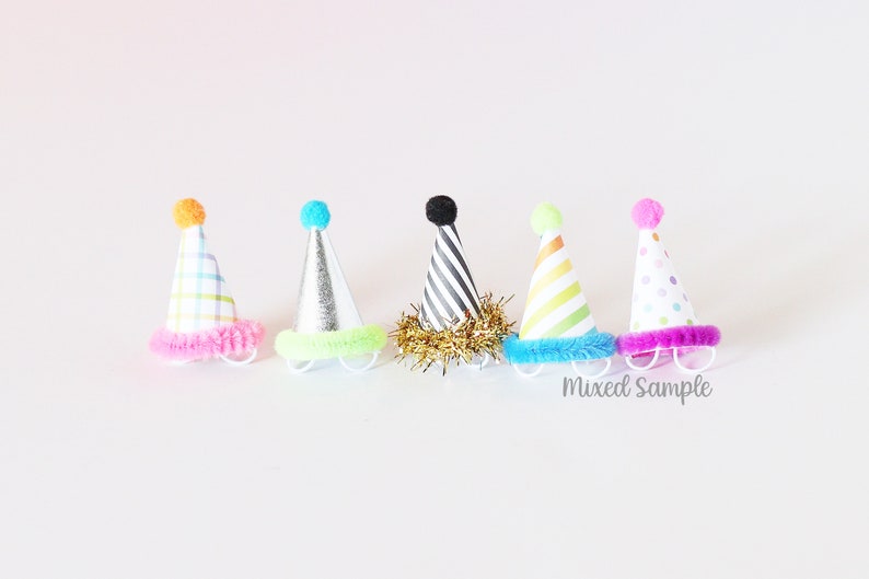 May include: Six colorful party hats with different patterns and pom-poms on top. The hats have a fuzzy trim around the bottom.  Mixed Sample.