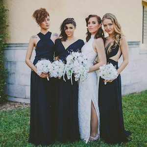 May include: Four bridesmaids in navy blue dresses holding white bouquets. The bride is wearing a white lace dress with a high neckline and a slit up the side.