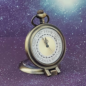 May include: Antique brass pocket watch with a cream-colored face. The watch features black Roman numerals and hands, with the words "LOST", "HOME", "MORTAL", "PERIL", "QUIDDITCH", "WORK", "SCHOOL", "GARDEN", and "IN TRANSIT" around the face.