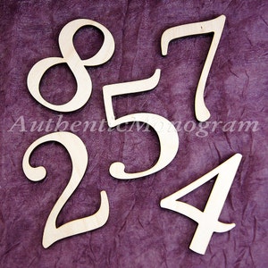 May include: Wooden numbers 2, 4, 5, 7, and 8 in a cursive font. The numbers are cut out of wood and are a light brown colour. The numbers are on a purple background.