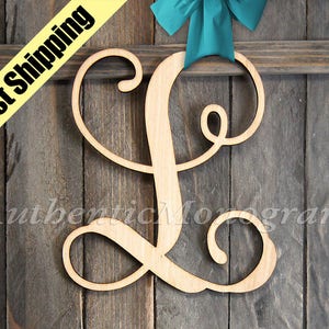 May include: A wooden cutout of the letter L in a cursive font. The letter is painted in a natural wood color and is hanging on a wooden background.