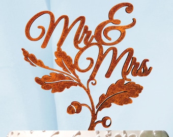 Könnte beinhalten: Rustikaler brauner Holz-Tortenaufsatz für Hochzeit mit den Worten "Mr & Mrs" und einem Blattdesign.