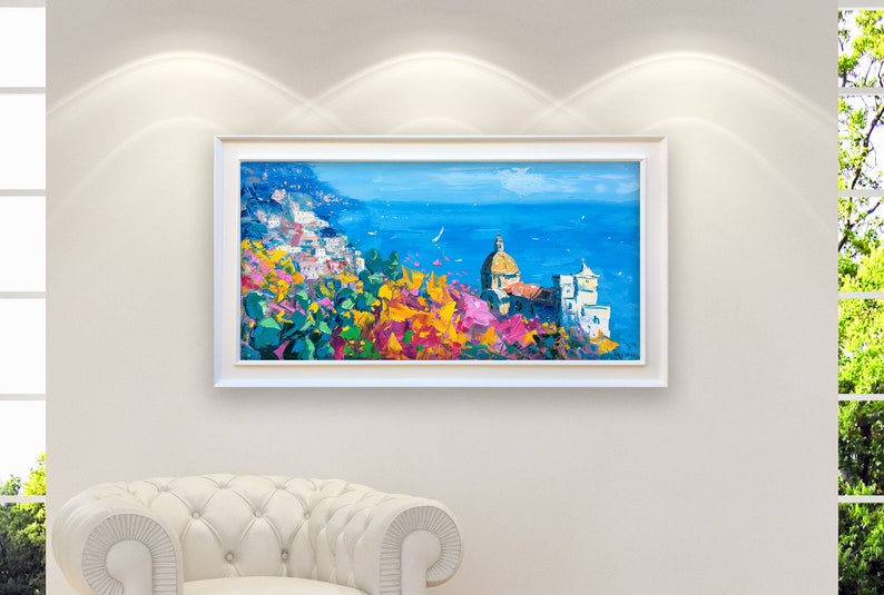 Panoramic Positano oil painting with church and flowers mounted in a white wooden frame in a modern home interior setting.
