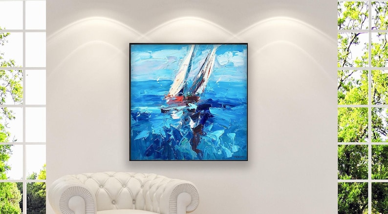 Original sailboats regatta painting with textured blue waves and white sails, displayed in a bright, modern living room above a white armchair with large windows and natural light.