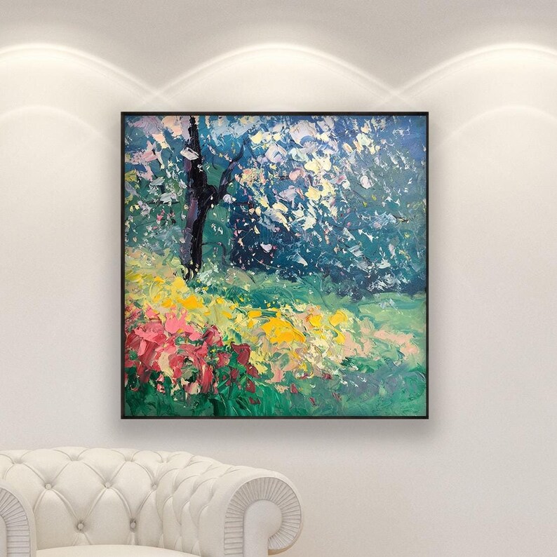 Impressionist oil painting of spring trees and colorful flowers hanging above a white armchair in a bright living room with spotlight lighting and garden view.