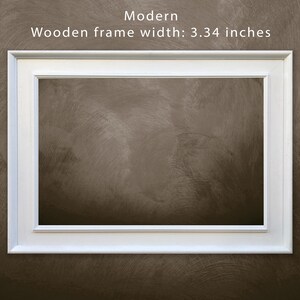 May include: White picture frame with a modern design. The frame is 3.34 inches wide.