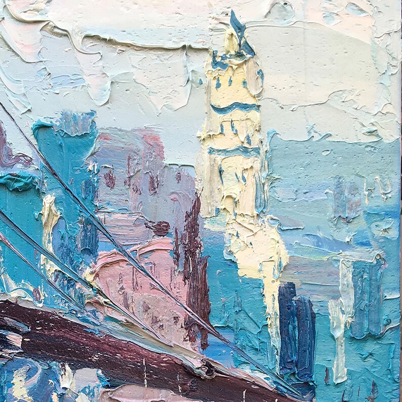 A detail of the Brooklyn Bridge oil painting with the cityscape  of New York with a tall building in the center. The building is painted in shades of yellow and white, while the surrounding buildings are painted in shades of blue and pink. The sky is painted in shades of blue and white.