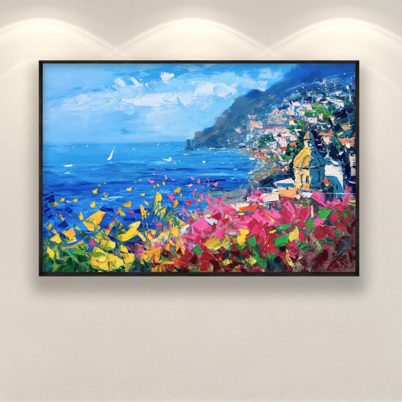 Hand-painted oil painting on canvas depicting Positano on the Amalfi Coast, with a blue seascape, coastal village and colorful foreground flowers, displayed in a black frame hanging on a wall in textured modern impressionist style.