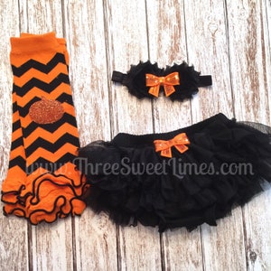 May include: Black and orange baby outfit with a pumpkin design on the leggings, a black tulle tutu with an orange bow, and an orange bow headband. www.ThreeSweetLimes.com