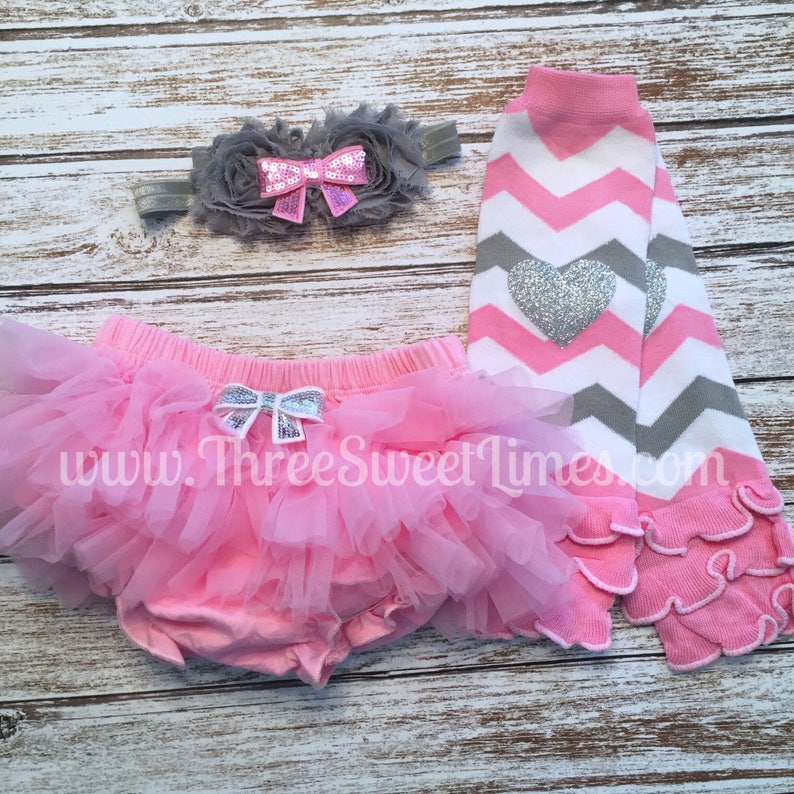 May include: Pink tutu skirt with a silver bow, pink and gray chevron leg warmers with a silver heart, and a gray flower headband with a pink bow.