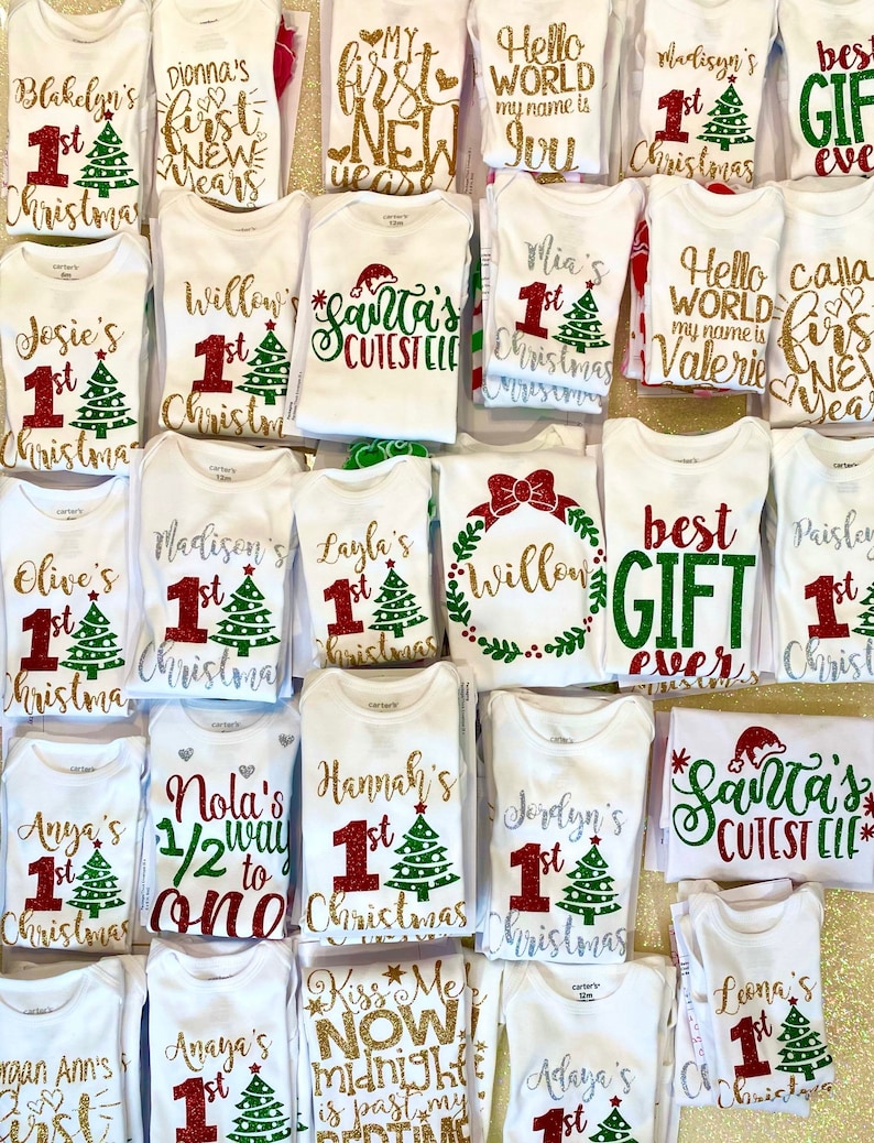 Puede incluir: Una colecci&oacute;n de bodies blancos con dise&ntilde;os de purpurina para una primera Navidad. Los bodies presentan varios dise&ntilde;os, incluyendo un &aacute;rbol de Navidad, Santa Claus y las palabras "primera Navidad".