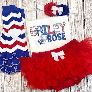 May include: Red, white, and blue baby outfit with a ruffled skirt, leg warmers, and a headband. The shirt has the name "BAILEY ROSE" in glittery letters with a red, white, and blue heart.