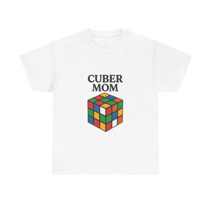 May include: White t-shirt with the text "CUBER MOM" above a colorful Rubik's Cube graphic. The cube features squares in red, blue, green, yellow, orange, and white. A casual, everyday tee.