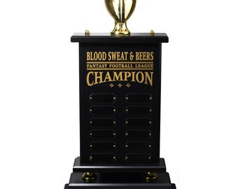 Può includere: Trofeo in legno nero con un pallone da football dorato in cima. Il trofeo ha una targa con la scritta "Blood Sweat & Beers Fantasy Football League Champion".