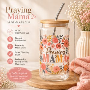 May include: A clear glass cup with a wooden lid and metal straw, featuring the text "Praying Mama" in a floral design. The cup is 16 oz and includes a straw cleaning brush. The design includes the words "Faith-Inspired, Beautiful, Meaningful, Made for You."