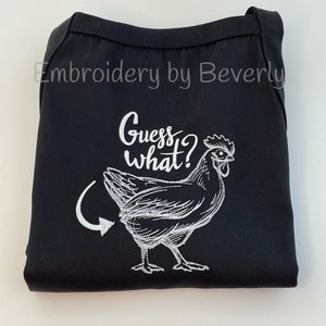 May include: Black apron with white embroidery of a chicken and the text "Guess what?" with an arrow pointing to the chicken's rear end.