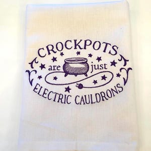 May include: White kitchen towel with purple embroidery that reads "Crockpots are just electric cauldrons". The embroidery includes a stylized image of a cauldron with a cord and plug.