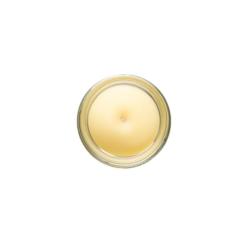 May include: A top view of a round, clear glass candle jar with a yellow wax candle inside. The candle has a small, round wick in the center.