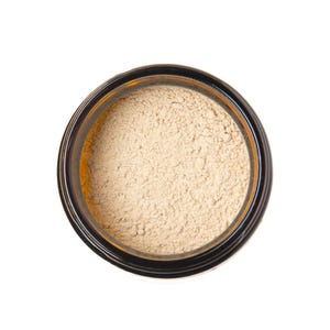 May include: A small glass jar with a brown lid filled with a light beige powder.