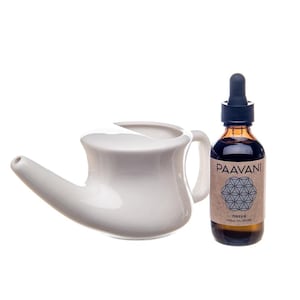 May include: White ceramic neti pot with a spout and handle, next to a brown glass bottle with a dropper. The bottle label reads "Paavani nasya nasal oil drops".