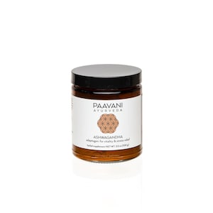 Puede incluir: Un tarro de vidrio marr&oacute;n con tapa negra que contiene un polvo marr&oacute;n. La etiqueta dice "Paavani Ayurveda" y "Ashwagandha adapt&oacute;geno para la vitalidad y el alivio del estr&eacute;s" con un peso neto de 3,5 oz (100 g).