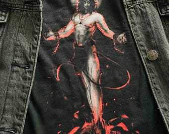 May include: A black t-shirt with a graphic print of a horned figure with a cross above its head. The figure is standing in a pool of red flames.