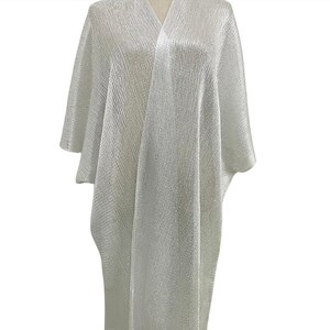 May include: A silver metallic mesh kimono with a fringe trim. The kimono is lightweight and sheer, making it perfect for layering.
