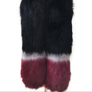 May include: A black faux fur scarf with a burgundy and white ombre trim. The scarf is soft and fluffy and would be a great addition to any winter wardrobe.