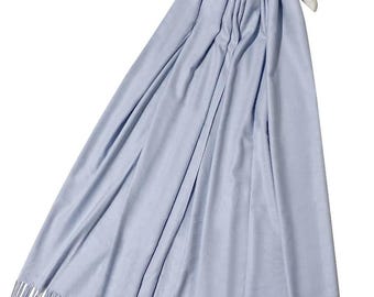 May include: A light blue scarf with fringe detail, draped over a white hanger. The scarf is made of a soft material and has a flowing, elegant appearance. The fringe is at the bottom edge of the scarf.