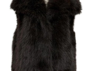 May include: A dark brown fur vest with a wide collar and short sleeves. The vest is displayed on a mannequin and has a soft, textured appearance. The garment is a stylish outerwear piece.