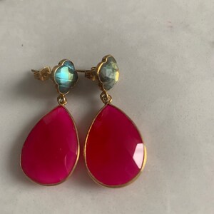 May include: A pair of dangle earrings with pink teardrop-shaped stones and blue flower-shaped stones.