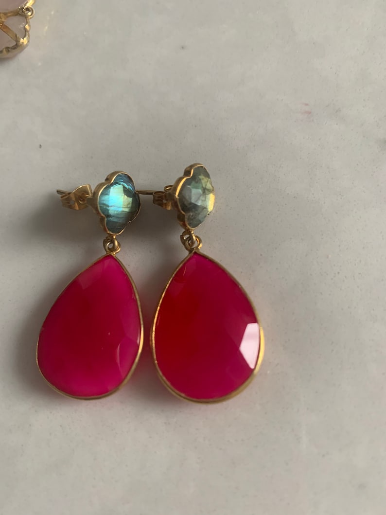 May include: A pair of dangle earrings with pink teardrop-shaped stones and blue flower-shaped stones.
