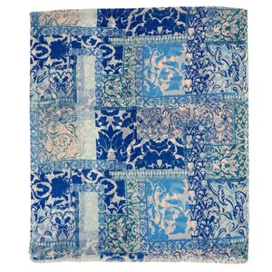 May include: A square, patterned textile in shades of blue and white. The design features a patchwork of floral and damask patterns in varying shades of blue, creating a visually rich and textured appearance. The overall aesthetic is elegant and decorative.