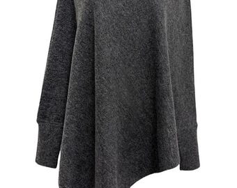 May include: A dark grey poncho-style sweater with long sleeves and a draped cowl neck. The asymmetrical hemline adds a modern touch to this cosy knitwear. The sweater is displayed on a mannequin.