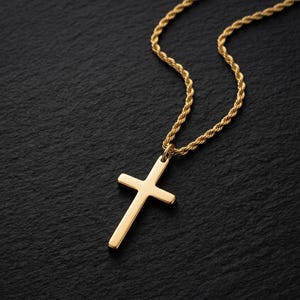 May include: A gold-colored cross pendant necklace. The cross is a simple, classic design with a smooth surface. The chain is a twisted rope style. The necklace is set against a dark, textured background.