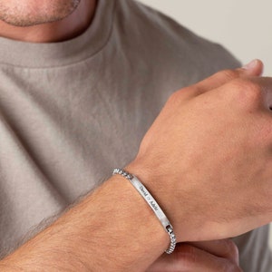 May include: A silver chain bracelet with a rectangular tag engraved with the text "David & Adele".