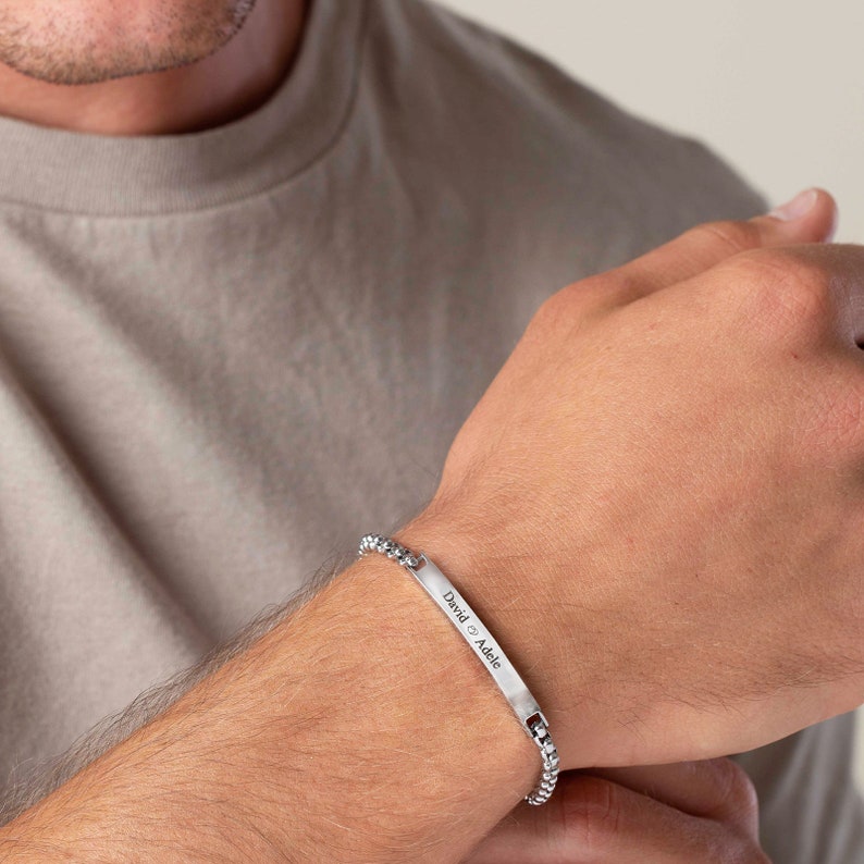 May include: A silver chain bracelet with a rectangular tag engraved with the text "David & Adele".