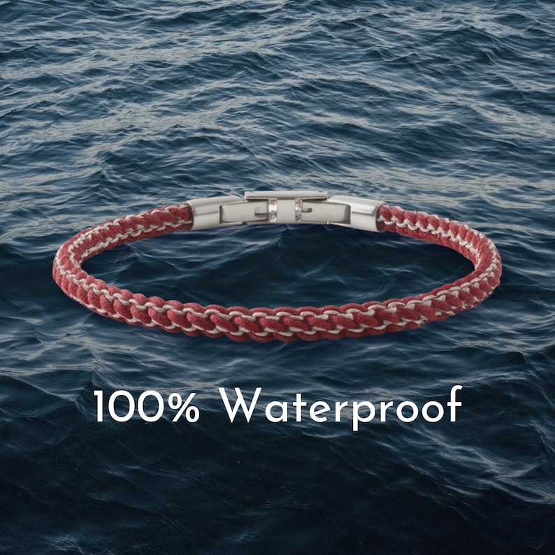 May include: Red and white braided bracelet with a silver clasp. The bracelet is shown against a backdrop of blue water. The text "100% Waterproof" is displayed in white.