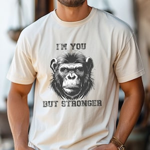 Peut inclure: Un t-shirt blanc avec une illustration noir et blanc d'un visage de singe et le texte "I'm you but stronger".