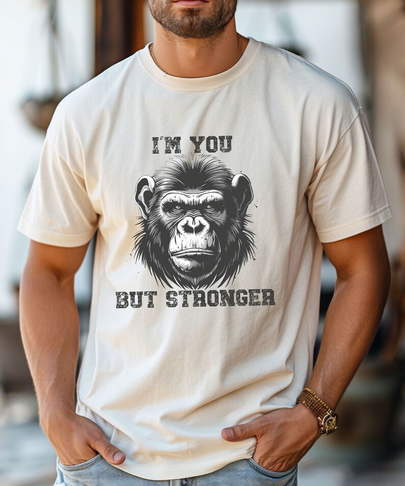 Peut inclure: Un t-shirt blanc avec une illustration noir et blanc d'un visage de singe et le texte "I'm you but stronger".