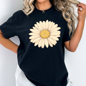 Puede incluir: Camiseta negra de gran tama&ntilde;o con un gran estampado de margarita blanca.