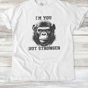 Peut inclure: T-shirt blanc avec une illustration noir et blanc d'un visage de singe et le texte "Je suis toi mais plus fort."