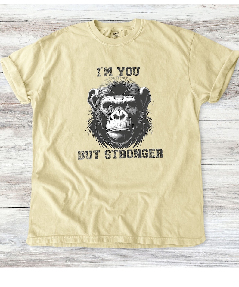 Peut inclure: Un t-shirt jaune clair avec une illustration en noir et blanc d'un visage de chimpanz&eacute;. Le texte "I'm you but stronger" est imprim&eacute; sous l'image.