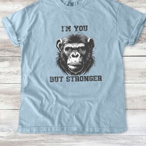Peut inclure: Un t-shirt bleu clair avec une illustration en noir et blanc d'un chimpanz&eacute;. Le texte "I'M YOU BUT STRONGER" est imprim&eacute; sur le t-shirt.
