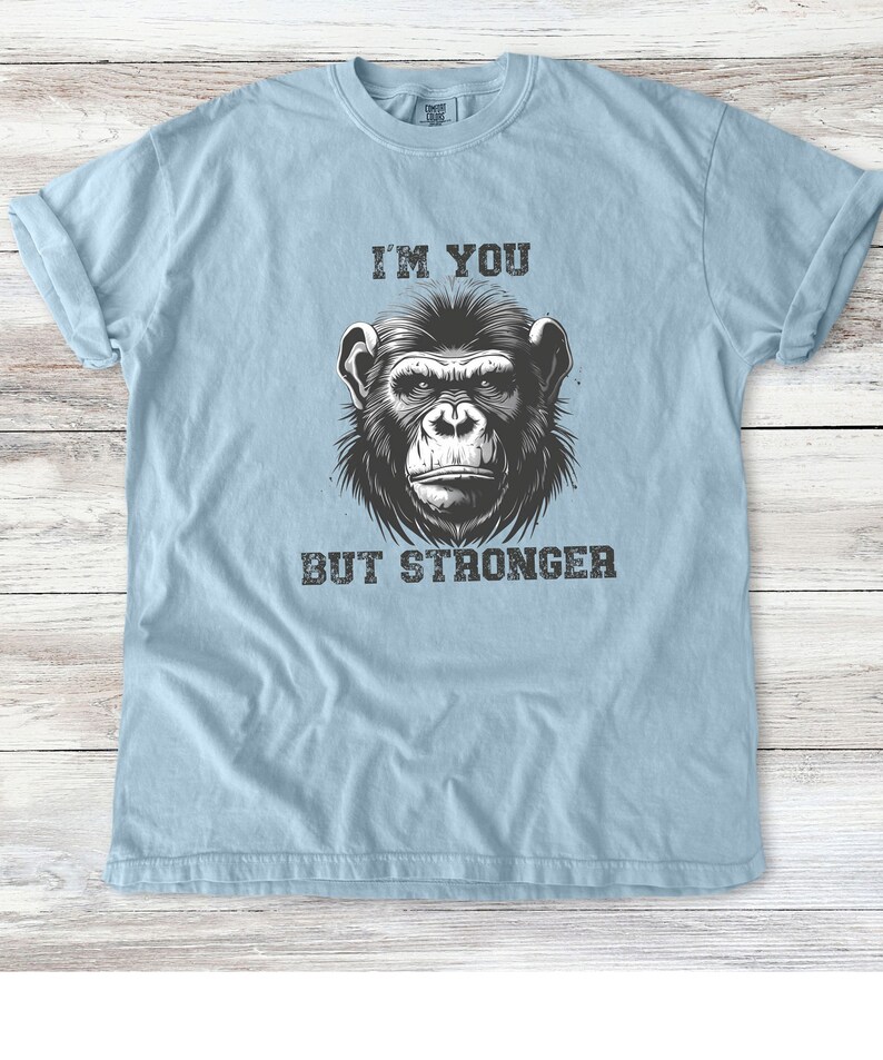 Peut inclure: Un t-shirt bleu clair avec une illustration en noir et blanc d'un chimpanz&eacute;. Le texte "I'M YOU BUT STRONGER" est imprim&eacute; sur le t-shirt.