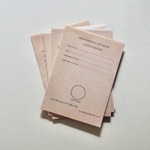 May include: A stack of light brown paper notebooks with black text. The cover reads DEPARTMENTAL NOTEBOOK (UNPERFORATED) with lines for Name of User, Rank, Date taken into use, and Date taken out of use, plus a circle for Serial number.