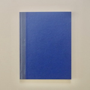 Peut inclure: Un carnet rectangulaire doté d'une couverture bleu profond unie et d'une bande verticale grise sur le bord gauche. La couverture présente une surface texturée et le carnet est orienté verticalement, offrant une vue frontale simple et épurée.