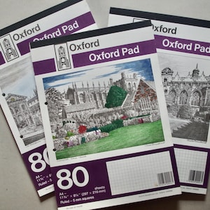 Może przedstawiać: Trzy notatniki Oxford Pad z ilustracjami architektonicznymi na okładkach. Każdy notatnik ma 80 kartek, format A4, w kratkę 5 mm. Notatniki mają fioletowy pasek z logo Oxford Pad.